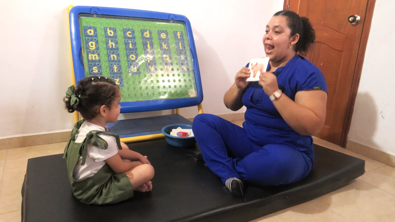 Profesional acompañando a una niña en terapia de lenguaje.